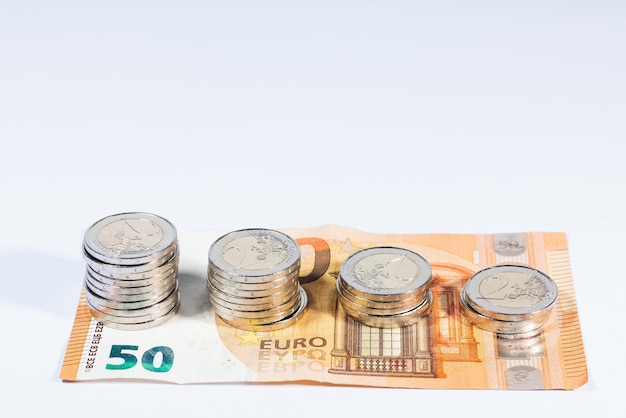 2 monete in euro e 50 banconote in euro su sfondo bianco