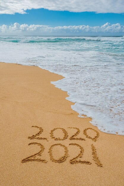 2020 2021 scritto nella sabbia con un'onda che lava via il 2020