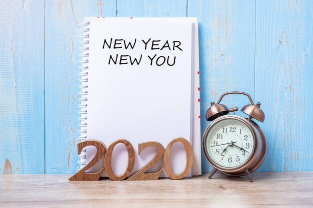 2020 Happy New Year New You con notebook, sveglia retrò e numero di legno sul tavolo