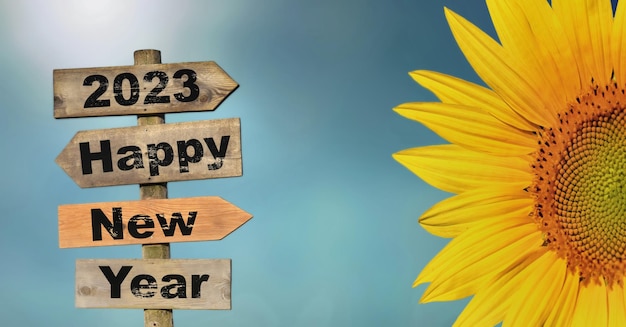 2023 felice anno nuovo scritto su un segnale di direzione con petali di fiori di sole sul cielo blu