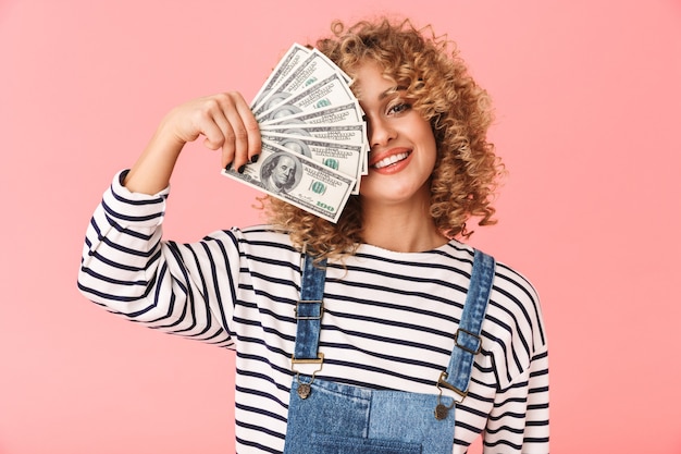 20s donna riccia eccitata che tiene fan di soldi del dollaro mentre levandosi in piedi