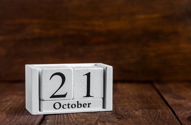 21 ottobre sul calendario accanto alla sveglia su uno sfondo di legno scuro Data del mese autunnale