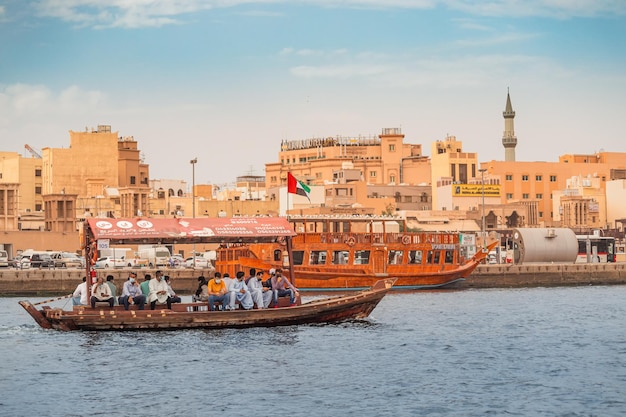 23 febbraio 2021 Dubai UAE Abra Dhow barche di legno trasportano i passeggeri da una riva del Dubai Creek all'altra con il minareto della moschea sullo sfondo