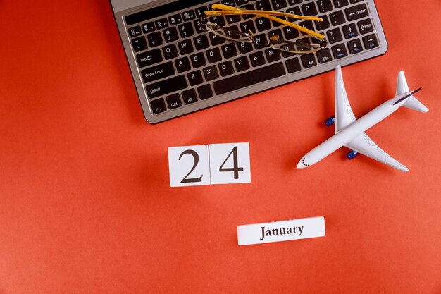 24 gennaio calendario con accessori sulla scrivania di lavoro area di lavoro sulla tastiera del computer, aereo, occhiali sfondo rosso