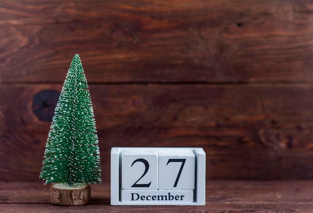 27 dicembre sul calendario. Calendario con un piccolo albero di Natale su uno sfondo di legno. Inverno. Spazio vuoto per il testo.