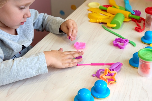 3 anni ragazza arti creative. Mani del bambino che giocano con la plastilina di argilla colorata. Autoisolamento Covid-19, formazione online, homeschooling. Ragazza del bambino che studia a casa, apprendimento a casa