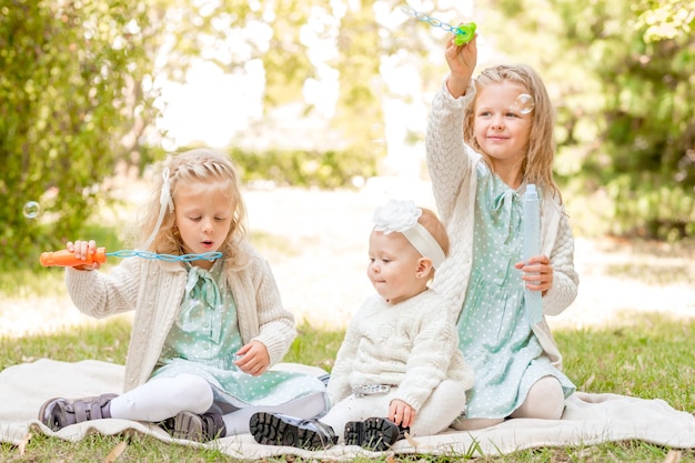 3 sorelle a un picnic che giocano con le bolle di sapone Vacanze estive 3 ragazze bionde