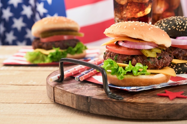 4 luglio American Independence Day cibo da picnic tradizionale American Burger e cocktail Bandiere americane e simboli degli Stati Uniti Vacanza picnic patriottica su sfondo di legno bianco Vista dall'alto