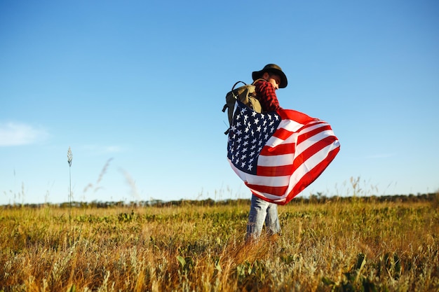 4 luglio bandiera americana viaggiatore con la bandiera dell'America l'uomo con un cappello una camicia zaino