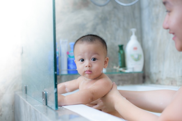 7 mesi di cute baby boy fare il bagno con sua madre nella stanza da bagno.