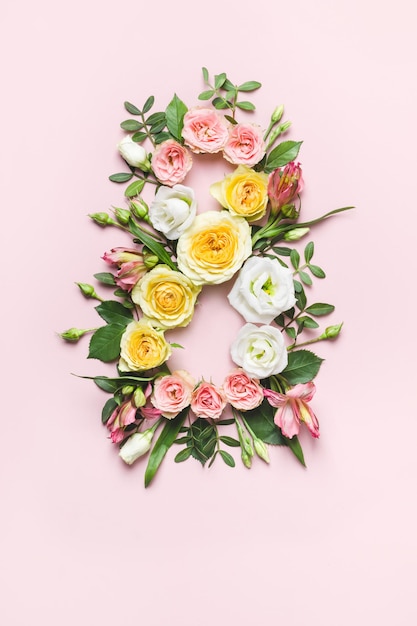 8 marzo concetto. Layout creativo fatto di fiori di rosa colorati su sfondo rosa. Biglietto di auguri per la festa della donna l'8 marzo.