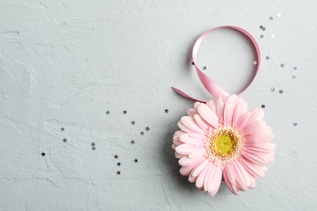 8 marzo, giornata internazionale della donna. Figura otto di nastro rosa con bella gerbera su grigio. Spazio per il testo