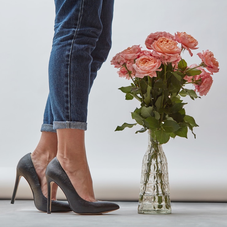 Photo a beautiful bouquet of pink roses in a glass vase on the floor next to a girls legs in jeans