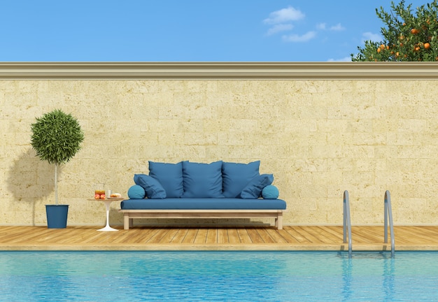 A bordo piscina divano blu in una giornata di sole