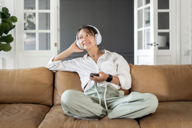 A casa ascoltando una playlist di musica con le cuffie nell'app un audiolibro di donna sta riposando