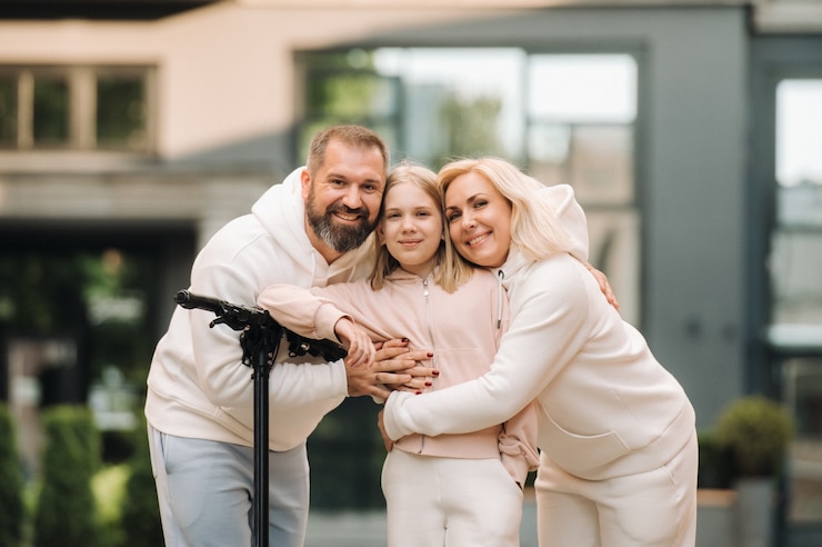 A family in white clothes stands in the city on electric scooters.