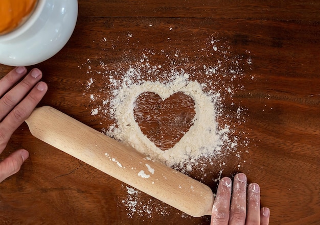 A forma di cuore con farina su fondo rustico in legno