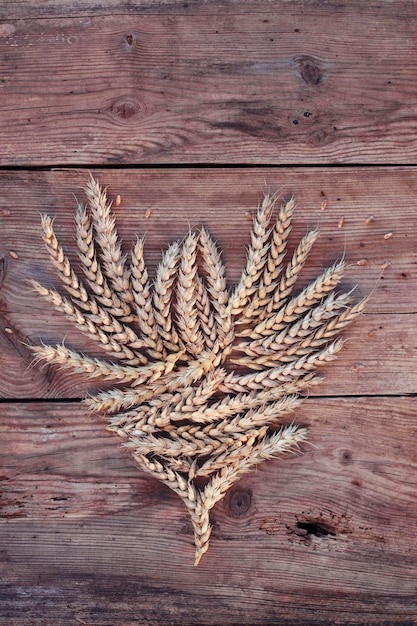 a forma di cuore di spighe di grano maturo su sfondo di legno