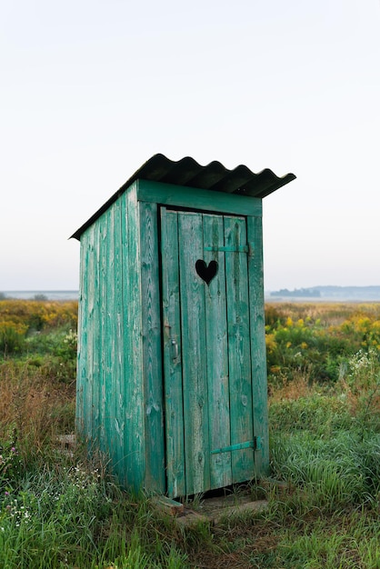 A forma di cuore sulla vecchia porta del bagno in legno servizi igienici verdi nel campo Attività ricreative all'aperto