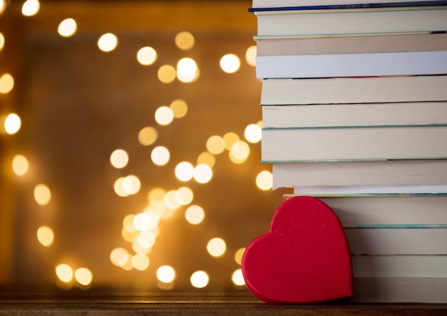 A forma di cuore vicino a pila di libri e luci fiabesche