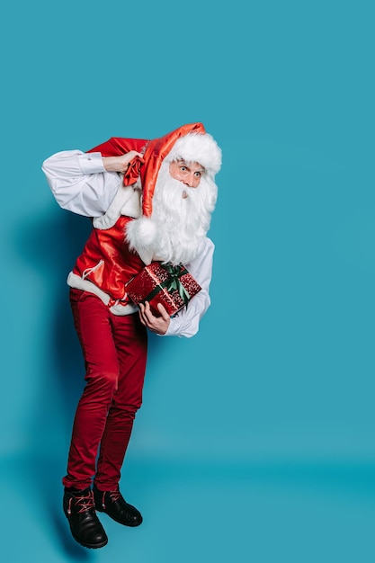 A grandezza naturale di Babbo Natale che trasporta un'enorme borsa di regali mentre tiene in mano una confezione regalo