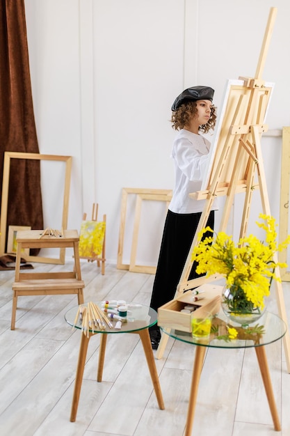 A grandezza naturale di un piccolo artista carino che dipinge un'immagine in studio mentre tiene la tavolozza dei colori