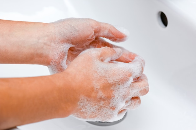 A Lavarsi le mani con sapone sotto il rubinetto con acqua