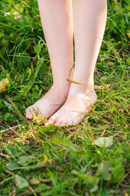 A piedi nudi del bambino che sta sull'erba verde.