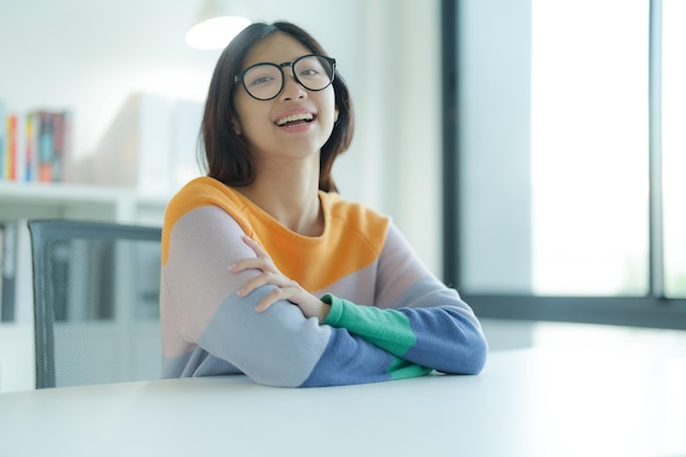 A prendersi una pausa dallo studio in biblioteca c'è una giovane donna sorridente o uno studente che indossa gli occhiali