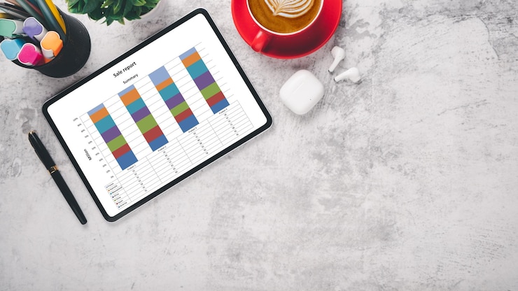 Photo a professional sales report on a tablet with colorful bar graphs a red coffee cup and office supplies on a marble surface