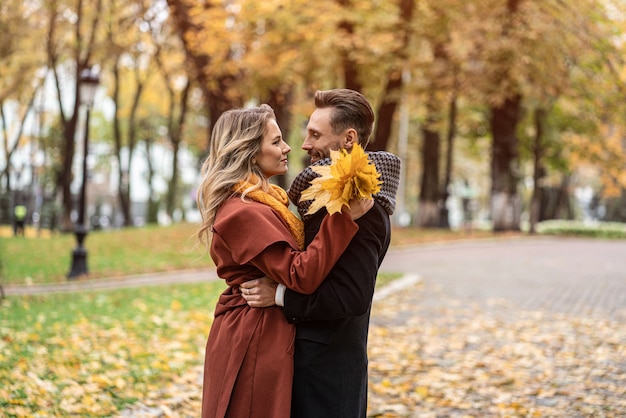 A proposito di un colpo di bacio. Marito e moglie si abbracciarono sorridendo guardandosi l'un l'altro nel parco d'autunno. All'aperto