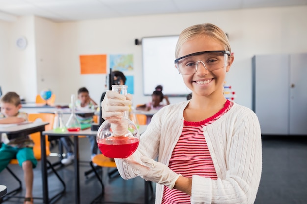 A pupil smiling at the camera with beaker