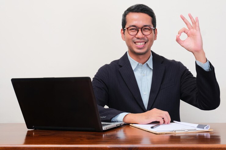 Photo a recruiter staff sitting on his workplace smiling and give ok hand sign