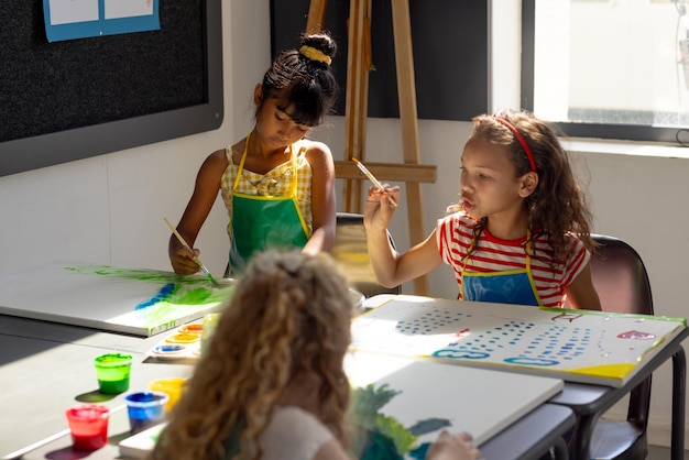 A scuola durante la lezione di arte diversi giovani studenti dipingono su tela