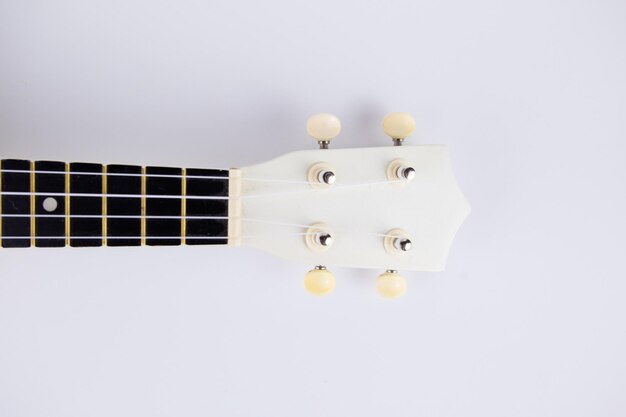 A stringhe di un bel primo piano di chitarra bianca su sfondo bianco ukulele