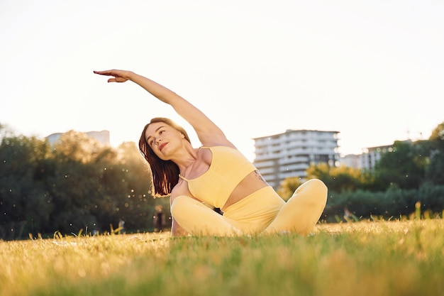 A terra Bella donna in abiti sportivi che fa esercizi di fitness all'aperto sul campo