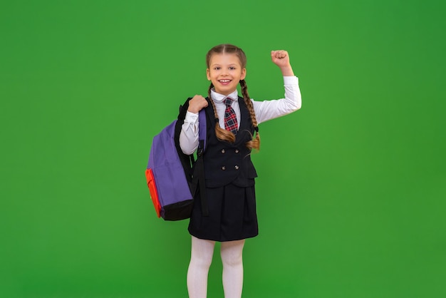 A una ragazza con una valigetta in uniforme scolastica piace molto la scuola uno studente sorridente si diverte isolato su sfondo verde studiando materiale scolastico e ottenendo un'istruzione scolastica