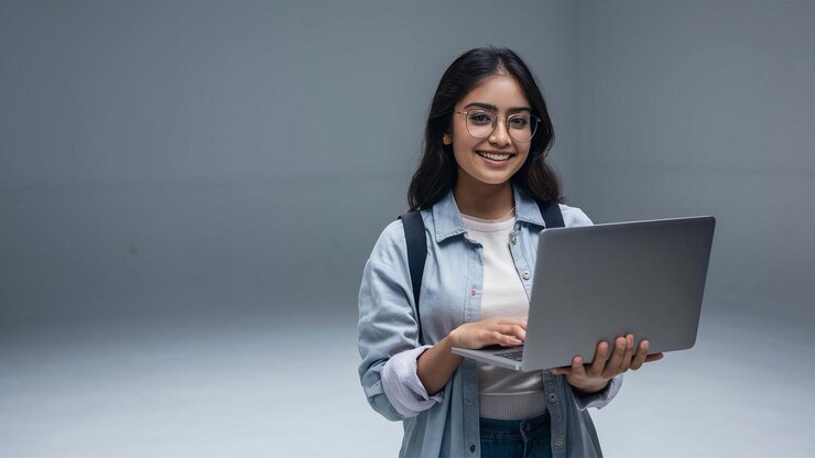 a woman is holding a laptop with a gray background
