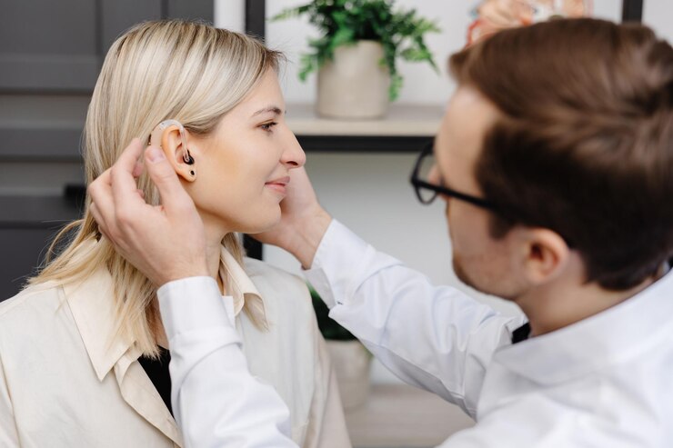 A young attractive otolaryngologist doctor gives a consultation to a female patient A doctor explains how to wear a hearing aid to a woman