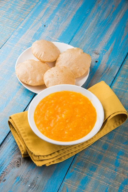 Aam Ras Puri è una deliziosa ricetta indiana servita come dessert di stagione, Aamras è semplice purea o polpa di mango, servita in una ciotola di ceramica e piatto su sfondo colorato o in legno. Messa a fuoco selettiva