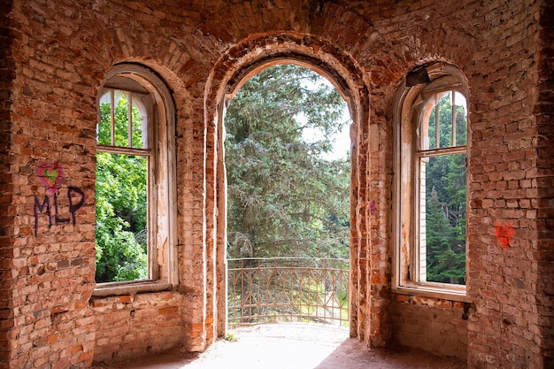 Abbandonato edificio in mattoni rossi finestre senza occhiali vista dall'interno di alberi verdi