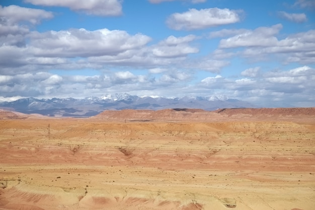 Abbandoni il paesaggio con un cielo blu nuvoloso e una catena montuosa ricoperta neve