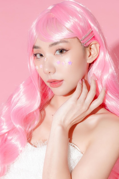 Abbastanza asiatica bella donna modello capelli lunghi con trucco fantasia sul viso e pelle perfetta su sfondo rosa isolato Trattamento facciale Cosmetologia chirurgia plastica