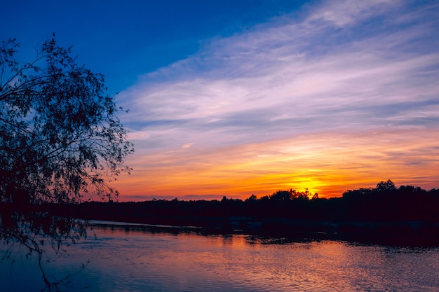 Abbellisca con il cielo dopo il tramonto sul fiume