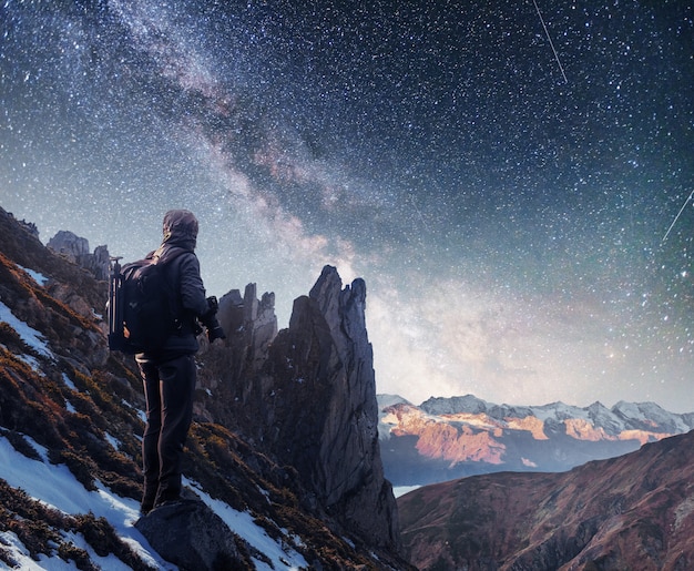 Abbellisca con la Via Lattea, le stelle del cielo notturno e la siluetta di un uomo diritto del fotografo sulla montagna.