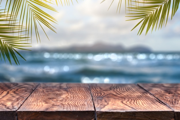 Abbellisca la vista con il vecchio piano d'appoggio di legno e la foglia della noce di cocco sopra il mare blu vago e la spiaggia di sabbia bianca con il chiaro fondo del cielo azzurro. Concetto Estate relax e festa.