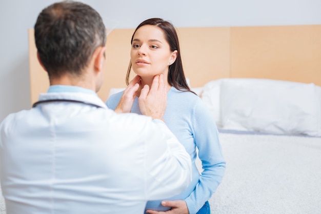 Abbi dei dubbi. Bruna felice che mette le mani sulla pancia e si siede di fronte al suo medico mentre guarda avanti