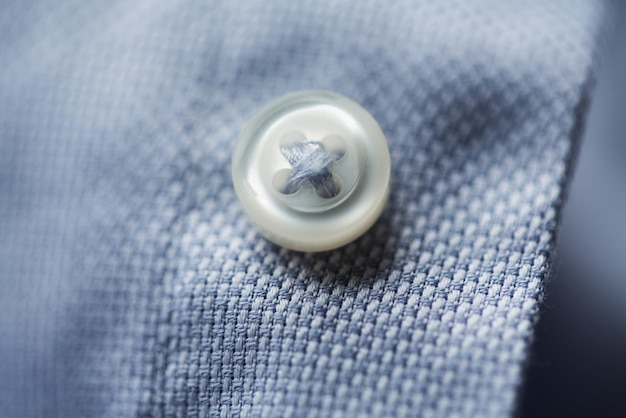 abbigliamento, abbigliamento formale, moda e concetto di oggetti - primo piano del bottone della camicia blu