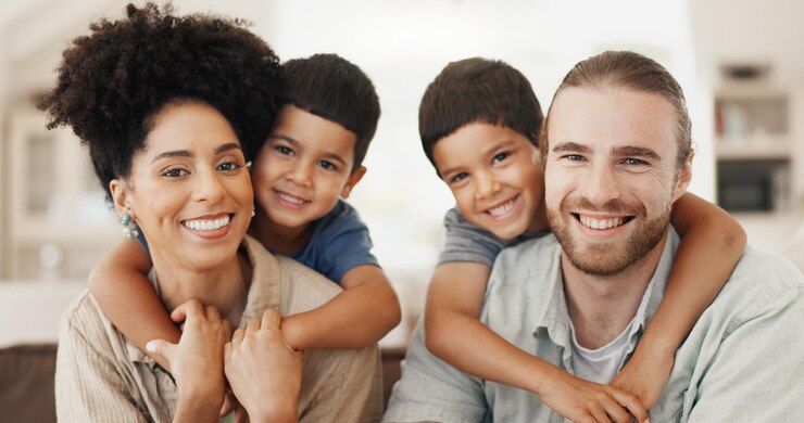 Foto abbracci d'amore e il volto di una famiglia su un divano per rilassarsi, legarsi e trascorrere del tempo insieme. sorriso felice e ritratto di bambini carini che abbracciano i loro giovani genitori interrazziali in una casa moderna.
