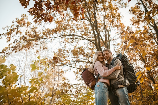 Abbracci della donna e dell'uomo che stanno nella foresta di autunno